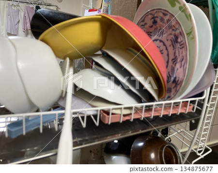 A pile of washed dishes and bowls on a draining rack A pile of washed dishes and bowls on a draining rack 134875677