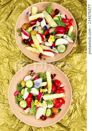 A bowl of mixed greens salad with edible flowers. 134876877
