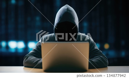 Faceless Hacker Using Laptop in Dark Environment Representing Cyber Crime and Data Theft 134877942