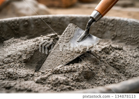 Construction Trowel Mixing Fresh Cement Concrete in Building Site Container 134878113