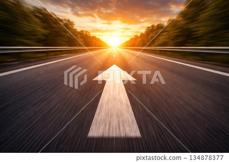 Empty Asphalt Road with White Arrow Leading Forward Toward Golden Sunset 134878377