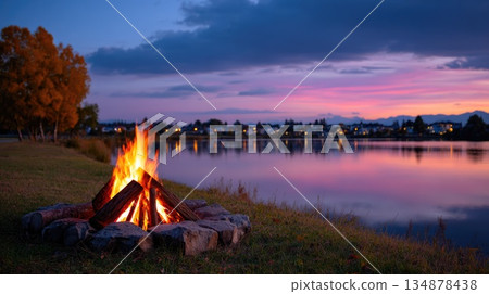Cozy Campfire Near Lake at Sunset with Reflections and Evening Atmosphere 134878438