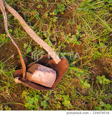 An antique leather sling lies on the ground 134879538