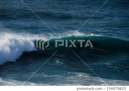 Majestic ocean wave rolling toward shore with foamy crest and deep blue water 134879825