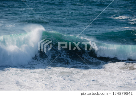 Powerful ocean wave curling and crashing with white foam in deep blue sea 134879841