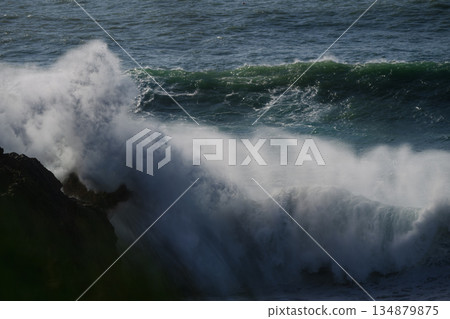Crashing sea waves slam against rugged cliffs in a dramatic ocean seascape 134879875