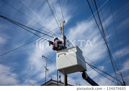 A worker performing electrical work on a utility pole using a high-altitude work vehicle 134879885