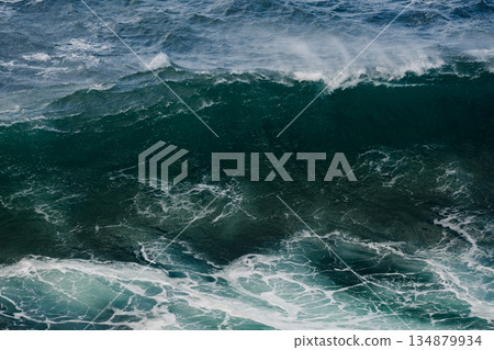 Massive ocean wave curling with deep blue water and white foam crashing near shore 134879934