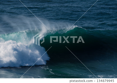 Powerful ocean wave curling over a dark turquoise sea with dramatic spray 134879945