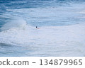Surfer riding a large ocean wave on a bright blue sea, dynamic coastal scene 134879965