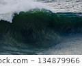 Powerful ocean wave curling over dark green water with white foam at the crest 134879966