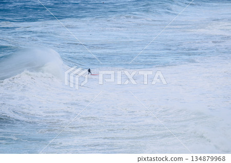 Surfer riding a massive wave alone in the open ocean, dramatic seascape 134879968