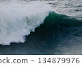 Massive ocean wave curling and breaking with white spray over deep blue water 134879976