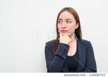Portrait of a young Asian businesswoman against white background thinking Portrait of a young Asian businesswoman against white background thinking 134880707