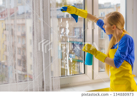 Woman cleaning window at home 134880973