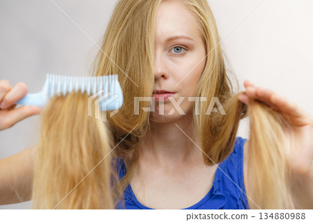Blonde girl combing her long messy hair Blonde girl combing her long messy hair 134880988