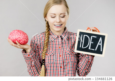 Woman holding idea sign and brain Woman holding idea sign and brain 134881126