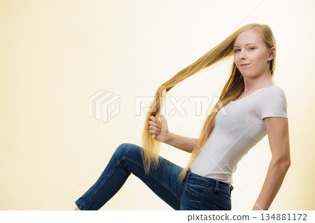 Blonde girl brushing her long hair 134881172