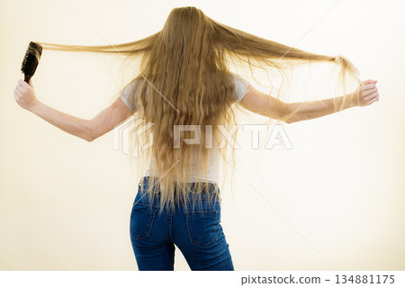 Blonde girl brushing her long hair Blonde girl brushing her long hair 134881175