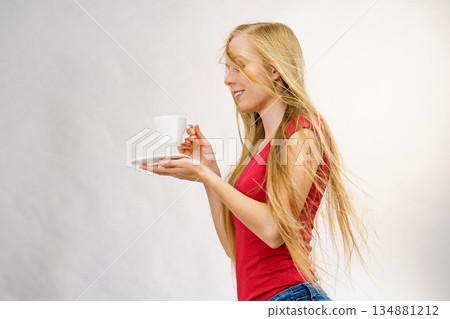 Blonde girl blowing hair holds coffee cup Blonde girl blowing hair holds coffee cup 134881212