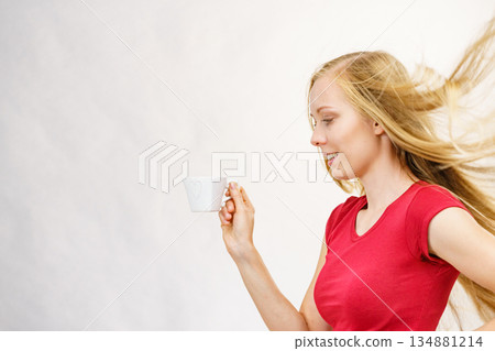 Blonde girl blowing hair holds coffee cup Blonde girl blowing hair holds coffee cup 134881214
