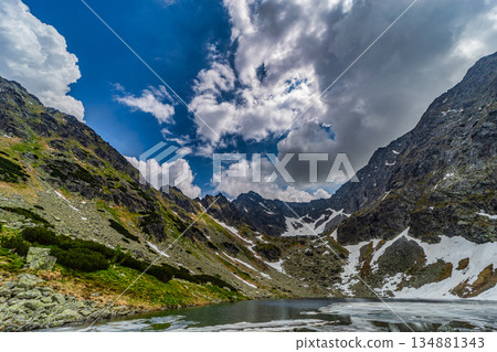 Panoramic view of a frozen glacial lake surrounded by snowy peaks in High Tatras Panoramic view of a frozen glacial lake surrounded by snowy peaks in High Tatras 134881343