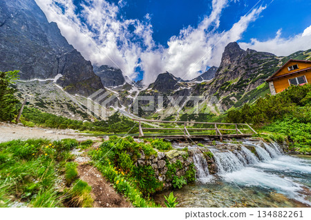 Wooden bridge over a mountain stream with peaks in High Tatras 134882261