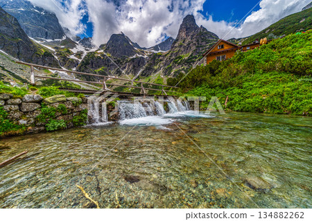 Wooden bridge over a mountain stream with peaks in High Tatras Wooden bridge over a mountain stream with peaks in High Tatras 134882262