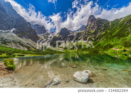 Pristine mountain lake with rocky peaks in High Tatras Pristine mountain lake with rocky peaks in High Tatras 134882264