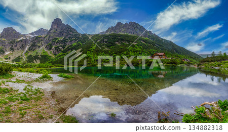 Panoramic reflection of a mountain hut in a crystal clear lake Panoramic reflection of a mountain hut in a crystal clear lake 134882318