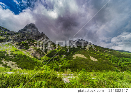 Traditional mountain hut by a lake under a dramatic stormy sky Traditional mountain hut by a lake under a dramatic stormy sky 134882347