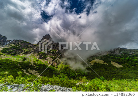 Traditional mountain hut by a lake under a dramatic stormy sky 134882360