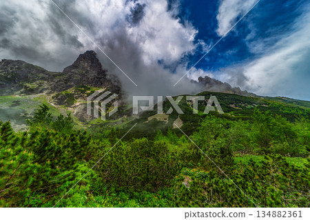 Traditional mountain hut by a lake under a dramatic stormy sky 134882361