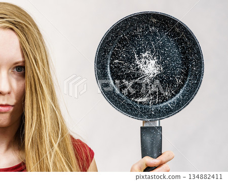 Girl holding scratched frying pan Girl holding scratched frying pan 134882411
