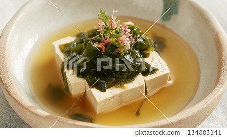 Gourmet Seaweed and Silken Tofu Soup with Pink Herb Garnish in Ceramic Bowl 134883141
