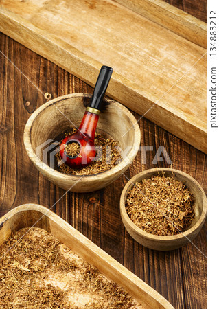 Smoking pipe with tobacco on a table. Smoking pipe with tobacco on a table. 134883212