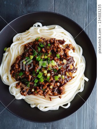 Minimalist flat lay of Zhajiangmian bowl with savory sauce topping. 134883235