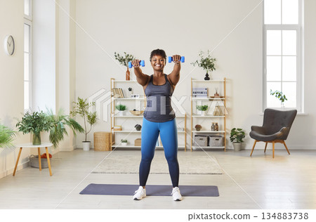 African american woman exercising at home with dumbbells African american woman exercising at home with dumbbells 134883738