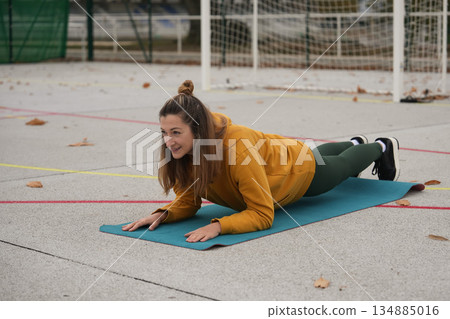 A woman stands in a plank position on a yoga mat A woman stands in a plank position on a yoga mat 134885016