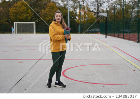 A sporty young woman with yoga mat in the stadium 134885017