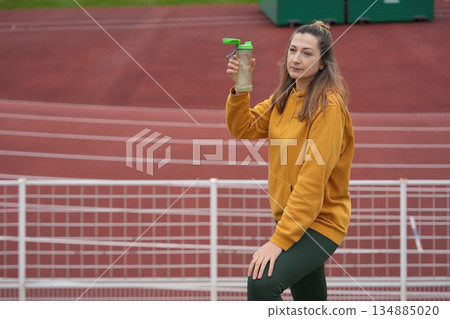 A woman drinking water at the stadium A woman drinking water at the stadium 134885020