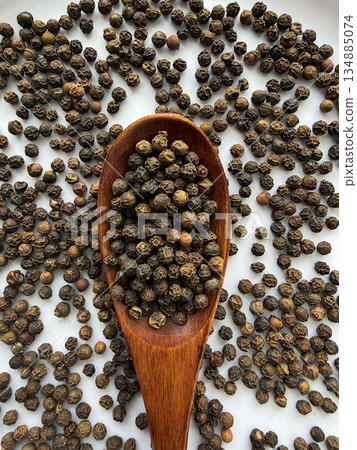 Macro Close-Up of Whole Black Peppercorns on Wooden Spoon Culinary Spice Background Macro Close-Up of Whole Black Peppercorns on Wooden Spoon Culinary Spice Background 134885074