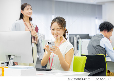 A woman operating a smartphone in the office A woman operating a smartphone in the office 134888272