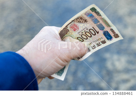 A crumpled 10,000 yen bill held tightly in the left hand 134888461