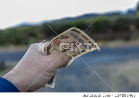 左手緊緊握著一張皺巴巴的10000日元鈔票 134888462