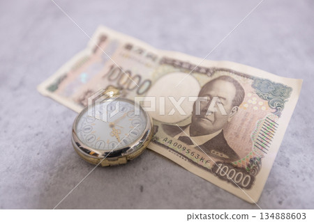 A wrinkled 10,000 yen bill and a pocket watch - the image of time being money 134888603