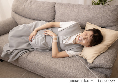 Pregnant woman lying on the sofa in pain Pregnant woman lying on the sofa in pain 134888726