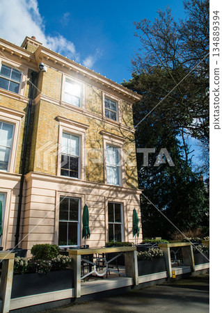在倫敦郊區邱園，一棟淺棕色磚砌建築和咖啡館沐浴在湛藍的天空和明媚的陽光下。 134889394