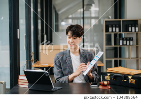 Asian female lawyer chatting online with client on laptop, smartphone  discussing details of lawsuit. in modern office 134889564