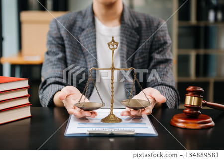 Male lawyer in the office with brass scale on wooden table. justice and law concept in morning light Male lawyer in the office with brass scale on wooden table. justice and law concept in morning light 134889581
